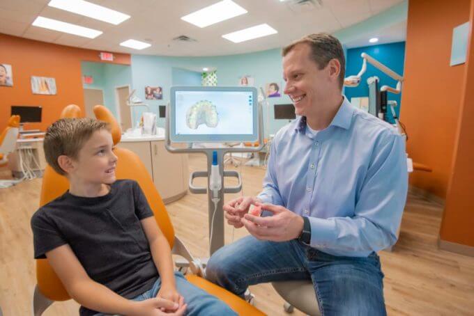 orthodontist with a young boy showing him how braces work